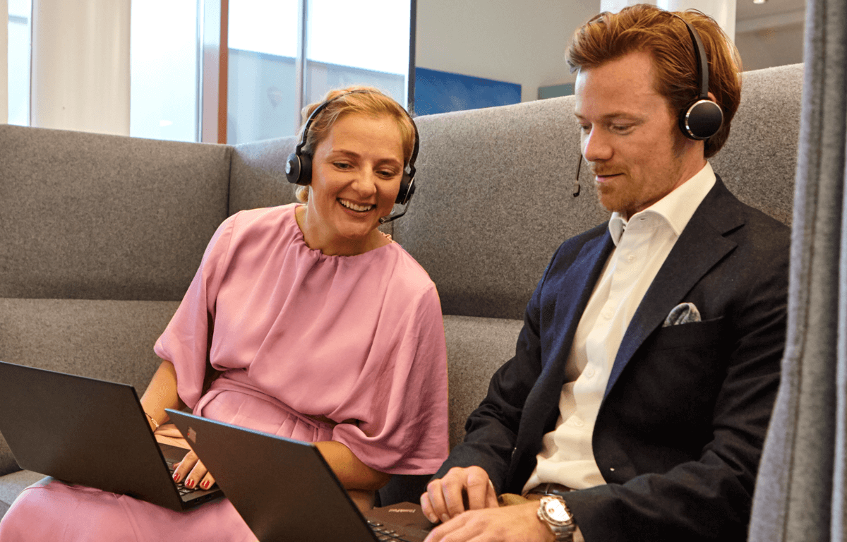 Bild på två kollegor som sitter i en soffa och tittar på en dator